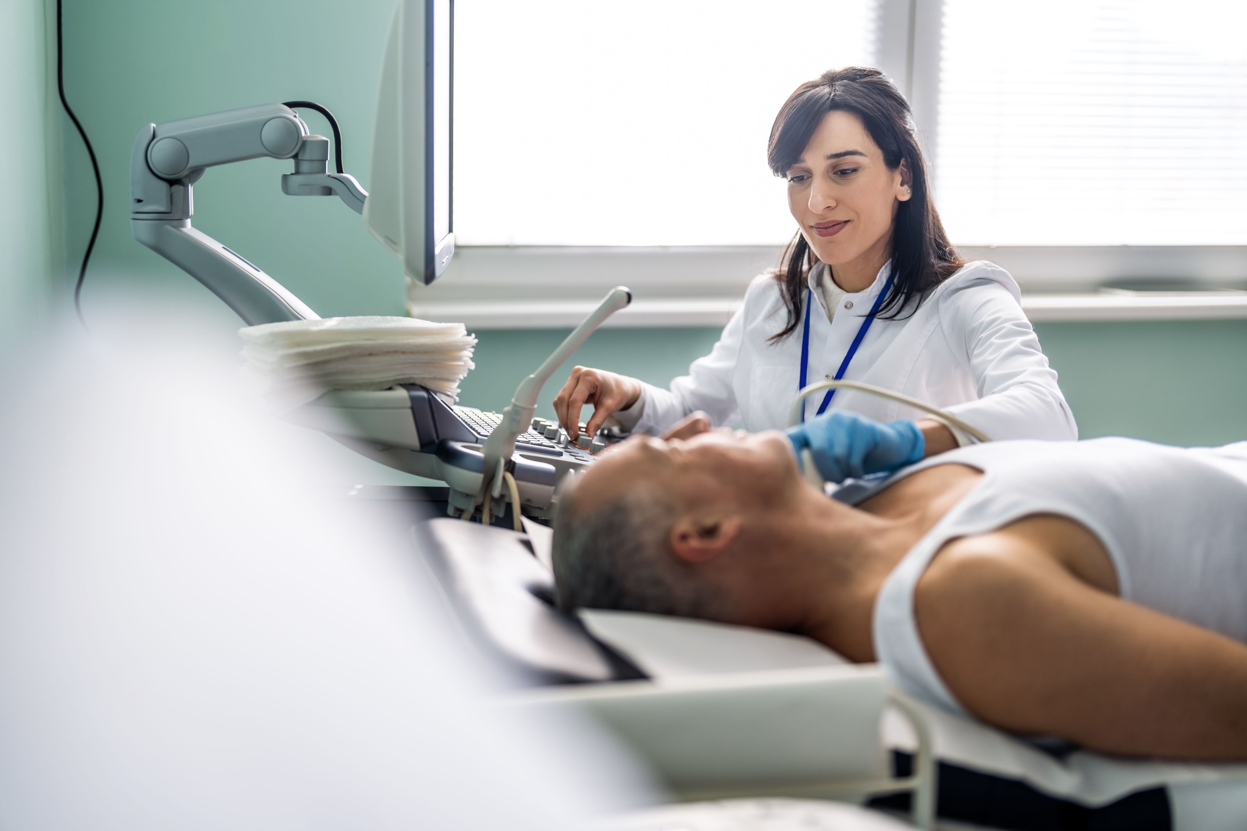 Female doctor examining a patient's neck with equipment.