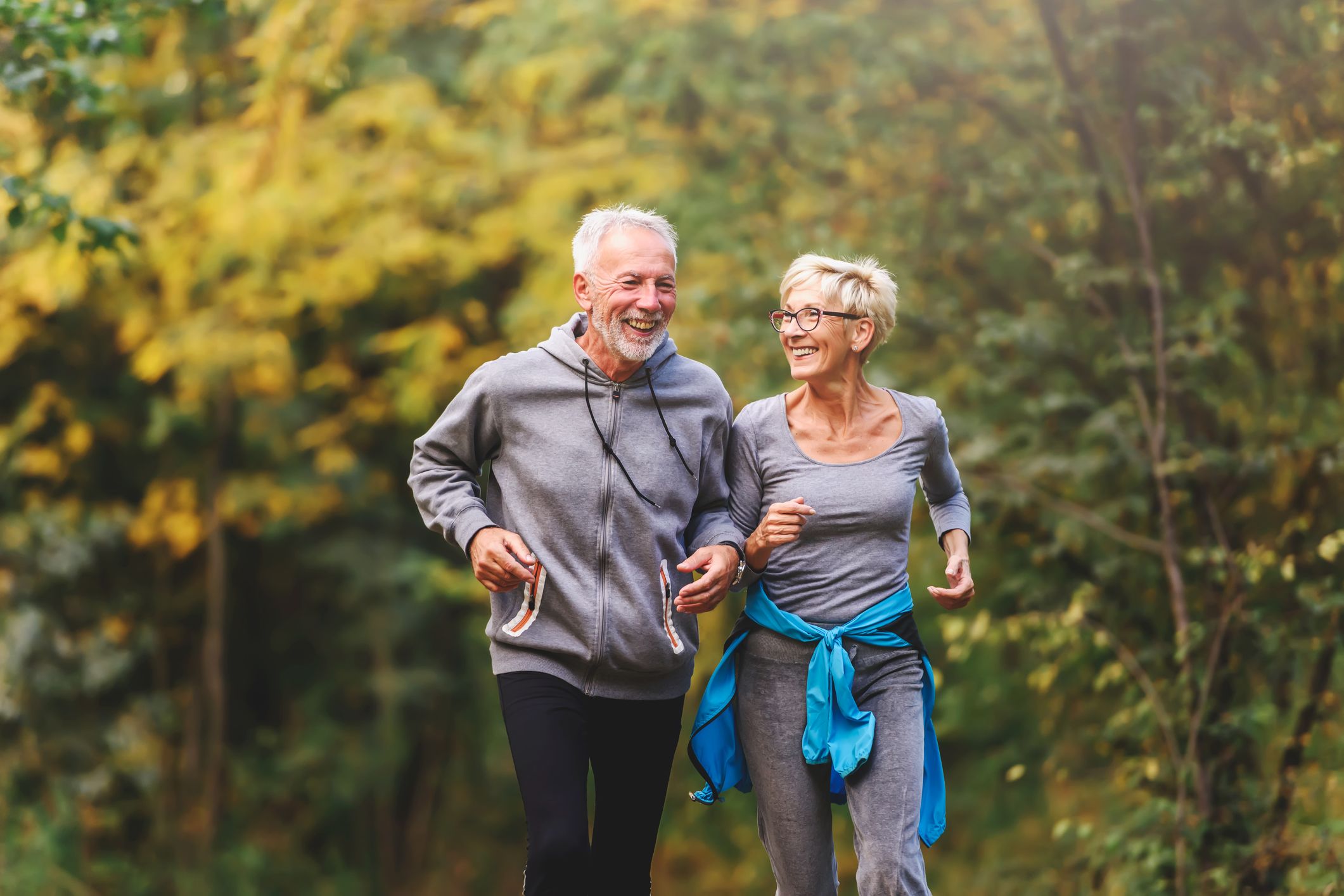 A smiling couple jogging in the park.